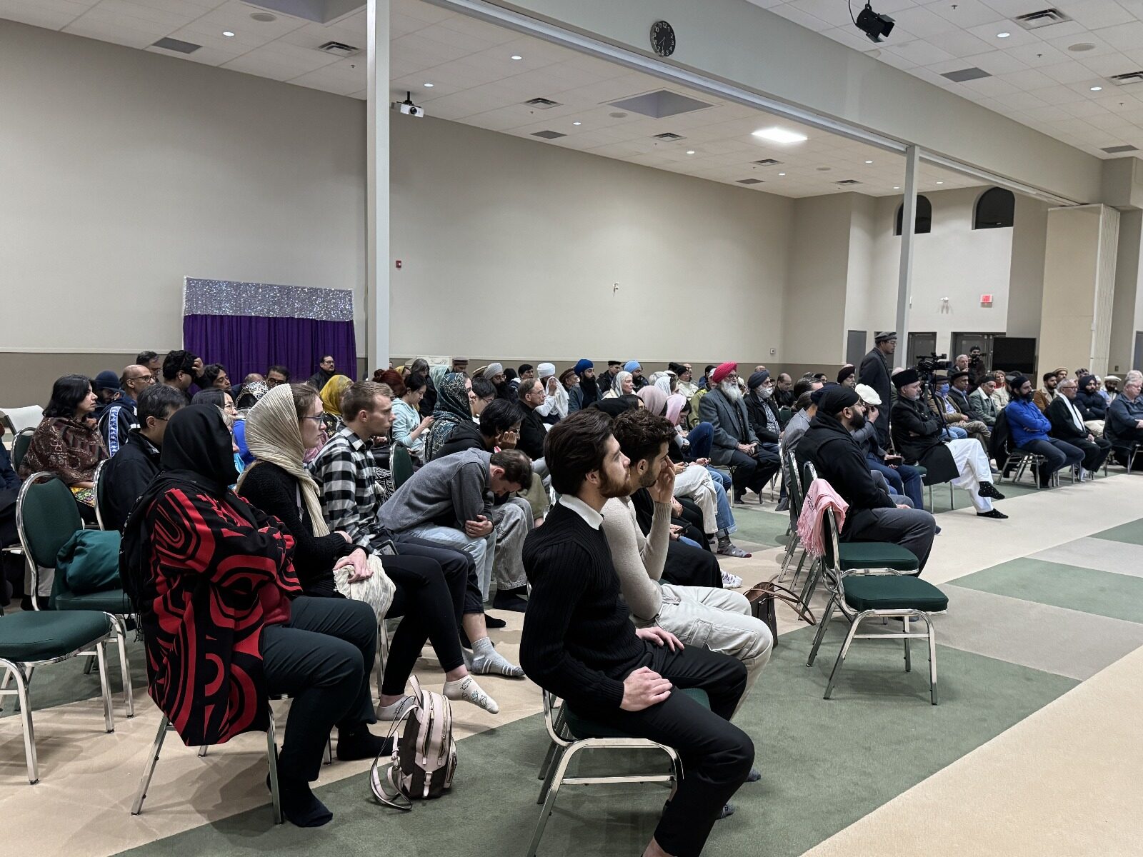 A diverse interfaith audience seated together during a community event